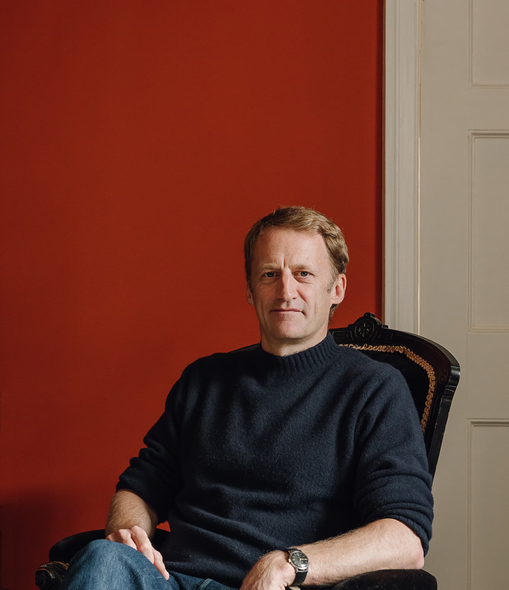 Guy Tobin seated against a red wall